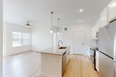 Located in Houston's 77070 corridor, this single-story 2-bedroom, 2-bathroom residence offers a clean, modern aesthetic with an efficient and functional layout. The open-concept living area seamlessly connects the living room, dining space, and kitchen, all unified by light-toned hardwood-style flooring and crisp white walls that enhance the sense of brightness throughout. The kitchen is a standout, featuring white shaker cabinetry, granite countertops, stainless steel appliances including a refrigerator, range, and microwave, a subway tile backsplash, and a central island with a sink and pendant lighting above. A dedicated built-in desk area with granite countertop and open shelving adds versatile utility space. The living area benefits from a ceiling fan and a window overlooking the exterior. Both bedrooms are comfortably sized with hardwood-style flooring, ceiling fans, and natural light from windows with blinds. The primary bedroom includes a walk-in closet outfitted with wire shelving. The bathrooms feature granite-top vanities with white cabinetry and modern light fixtures. An in-unit laundry area houses a top-load washer, and a private patio completes this well-appointed home.
