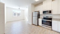 Located at 150 Inspiration Ave in Bluffton, SC, this two-bedroom, one-bathroom residence offers a well-organized, single-floor layout designed for comfortable everyday living. The open-concept kitchen flows seamlessly into the living area, creating a bright and airy atmosphere. The kitchen is outfitted with white shaker-style cabinetry extending to the ceiling, granite countertops, light wood-look vinyl flooring, and a full suite of stainless steel appliances including a refrigerator, electric range, microwave, and dishwasher. The adjacent living area benefits from large windows that invite abundant natural light, complemented by a ceiling fan overhead. Both bedrooms feature soft wall-to-wall carpeting and sizable windows fitted with blinds, providing a comfortable and private retreat. The primary bedroom offers a generous footprint, while the second bedroom is comparably appointed. The shared bathroom includes a granite-topped vanity with white cabinetry, an undermount sink, and a large mirror, maintaining the clean, cohesive aesthetic found throughout the home. A dedicated closet provides additional storage convenience. The residence presents a bright, neutral palette throughout, creating a welcoming and move-in-ready environment.