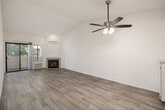 This single-floor, 3-bedroom, 2-bathroom residence offers a well-organized layout with light wood-style flooring running throughout the main living areas and bedrooms. The open living room is a standout feature, highlighted by vaulted ceilings, a ceiling fan with integrated lighting, a tile-surround fireplace, and a sliding glass door that leads to an outdoor patio area, allowing natural light to fill the space. Adjacent to the living room, the galley-style kitchen is efficiently designed with white cabinetry, granite-look countertops, a stainless steel sink, and white appliances, including a gas range and refrigerator. The primary bedroom offers a comfortable footprint with a mirrored sliding-door closet and direct access to one of the two bathrooms. Additional bedrooms are bright and well-proportioned, each featuring large windows with blinds and light wood-style flooring. One bedroom includes sliding glass door access to an outdoor area. Both bathrooms are clean and functional, each featuring a full tub-shower combination, window for natural light, and white fixtures with chrome hardware. A connecting hallway ties the rooms together, completing this practical and thoughtfully arranged single-level home.