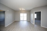This well-appointed single-floor unit offers a thoughtfully designed layout with modern finishes throughout. The centerpiece of the space is a sleek, contemporary kitchen featuring rich dark wood cabinetry, white quartz countertops, a classic subway tile backsplash, and a full suite of stainless steel appliances including a refrigerator with ice maker, range, microwave, and dishwasher. A central island with pendant lighting above provides additional prep space and adds to the kitchen's open, functional character. Light wood-style flooring runs through the kitchen and living areas, creating a warm, cohesive aesthetic. The living area is generously proportioned, filled with natural light, and features sliding glass doors that open to a private balcony with open city views. The bedrooms are carpeted for comfort, with large windows that bring in additional natural light and exterior views. A walk-in closet with wire shelving provides ample organized storage. The bathroom is finished with clean, neutral tile, a tub-shower combination with glass enclosure, a white quartz vanity, and a large mirror. A dedicated laundry area houses a full-size side-by-side washer and dryer, adding everyday convenience to this modern, move-in ready space.