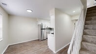 Located in Indianapolis, Indiana, this two-story, 2-bedroom, 2-bathroom home offers a thoughtfully updated interior with a clean, modern aesthetic. The main floor features wood-look hardwood-style flooring that flows from the living area through the kitchen and hallway. The kitchen is outfitted with crisp white shaker cabinetry, light countertops, a tile backsplash, and stainless steel appliances including a refrigerator, dishwasher, and gas range. A partial wall divides the kitchen from the adjacent living and dining area, creating an open yet defined layout. Recessed lighting throughout the main level adds a bright, welcoming atmosphere. The second floor hosts both bedrooms, each carpeted for comfort. The spacious primary bedroom connects to a closet area with a stacked washer and dryer conveniently located nearby. The second bedroom features a window that allows natural light into the space. Both bathrooms are finished with modern black fixtures, grey tile flooring, and white vanities. One bathroom features a tub-shower combination with a stylish linear mosaic tile surround, while the other offers a vanity with a rounded mirror and sleek hardware. The overall design is cohesive, neutral, and move-in ready.