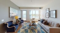 Located at 10826 Austin St NE in Blaine, Minnesota, this single-floor residence offers a well-designed layout with a bright, open feel throughout. The living room is a standout space, bathed in natural light from large windows and a sliding glass door that frames serene waterfront views, creating a welcoming and airy atmosphere. Warm hardwood-style flooring runs through the main living areas, complementing the neutral color palette.

The kitchen is thoughtfully appointed with warm maple cabinetry, granite countertops, a full suite of white appliances including a range, dishwasher, refrigerator, and microwave, and a breakfast bar island that provides additional seating and prep space. Recessed lighting adds a polished finish to the space.

The primary bedroom features plush carpeting, a closet, and direct access to an en-suite bathroom with a vanity, toilet, and tub-shower combination. A second bedroom also offers carpeted floors and ample closet storage. A second full bathroom mirrors the clean, functional design of the first. The convenience of an in-unit washer and dryer adds to the practicality of this well-appointed residence. Overall, the space balances comfort and functionality with appealing waterfront-adjacent surroundings.