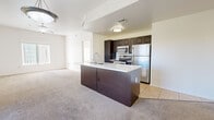 Located at 2656 W Broadway Blvd in Tucson, Arizona, this apartment offers a well-designed single-floor layout with three bedrooms and two full bathrooms. The open-concept living and kitchen area serves as the heart of the unit, where a central kitchen island with a built-in sink and white countertop anchors the space. Dark espresso cabinetry lines the kitchen walls, complemented by a full suite of stainless steel appliances including a refrigerator, range, and microwave. Tile flooring in the kitchen transitions to soft neutral carpet throughout the living and bedroom areas. The living room is generously proportioned, featuring a ceiling fan and sliding glass doors that open to a private balcony with outdoor views. The primary bedroom is a comfortable retreat with a ceiling fan, a large window with vertical blinds for natural light control, and a walk-in closet with wood hanging rods. Both bathrooms are finished with dark wood vanities, white countertops, large mirrors, and tile flooring. One bathroom features a tub-shower combination with tiled surround. The second bathroom includes a separate shower and additional drawer storage. Throughout the unit, neutral white walls and consistent finishes create a clean, cohesive aesthetic.