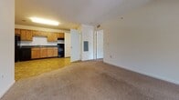 Located at 1220 N King Street in Hampton, Virginia, this single-floor residence offers a practical and comfortable layout designed for everyday living. The kitchen is well-equipped with warm honey-toned cabinetry, dark countertops, black appliances including a refrigerator, range, and dishwasher, and a double-basin sink. Stone-pattern tile flooring runs throughout the kitchen and connects seamlessly to an in-unit laundry area. The open living area transitions from tile to plush carpet, creating a warm and inviting atmosphere. An arched architectural detail adds a subtle design element to the interior. The bedrooms are generously proportioned, featuring soft carpeting, bright windows with blinds that allow ample natural light, and access to closet space. The bathrooms are finished with warm tile flooring, wood-toned vanities with white countertops, and full tub-shower combinations. One bathroom includes an adjacent walk-in closet with built-in shelving. Throughout the unit, neutral white walls and consistent finishes create a clean, cohesive aesthetic. The layout flows logically between living, kitchen, and private spaces, offering a functional and comfortable living environment in the Hampton Roads area.