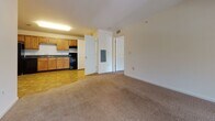 Located at 1220 N King Street in Hampton, Virginia, this single-floor residence offers a practical and comfortable layout designed for everyday living. The kitchen is well-equipped with warm honey-toned cabinetry, dark countertops, black appliances including a refrigerator, range, and dishwasher, and a double-basin sink. Stone-pattern tile flooring runs throughout the kitchen and connects seamlessly to an in-unit laundry area. The open living area transitions from tile to plush carpet, creating a warm and inviting atmosphere. An arched architectural detail adds a subtle design element to the interior. The bedrooms are generously proportioned, featuring soft carpeting, bright windows with blinds that allow ample natural light, and access to closet space. The bathrooms are finished with warm tile flooring, wood-toned vanities with white countertops, and full tub-shower combinations. One bathroom includes an adjacent walk-in closet with built-in shelving. Throughout the unit, neutral white walls and consistent finishes create a clean, cohesive aesthetic. The layout flows logically between living, kitchen, and private spaces, offering a functional and comfortable living environment in the Hampton Roads area.