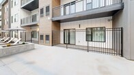 Located at 375 W Whitney Ave in Salt Lake City, Utah, this contemporary multi-story residential community showcases a striking modern design with a mixed exterior palette of board-and-batten siding, warm wood-toned panels, crisp white panels, and dark accents. The architecture wraps around a series of thoughtfully designed outdoor amenity spaces that serve as the heart of the community.

A resort-style pool and adjoining spa take center stage, surrounded by a spacious deck outfitted with lounge chairs and market umbrellas. The elevated pool deck offers sweeping views of the Wasatch Mountains, providing a dramatic natural backdrop. Black metal railings frame the deck, lending a refined, modern touch throughout.

Multiple courtyard areas extend the outdoor living experience, featuring pergola-covered gathering zones equipped with outdoor kitchens and grilling stations, fire pit seating areas, and comfortable lounge furniture arranged for both socializing and relaxation. String lights overhead add warmth to the evening atmosphere.

Ground-level units open directly onto the courtyards via sliding glass doors and private fenced patios, while upper-floor residences feature private balconies overlooking the amenity areas. The cohesive architectural design, layered outdoor programming, and prominent mountain views combine to create a vibrant, amenity-rich community environment.