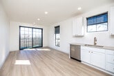 This thoughtfully designed single-floor unit offers a bright, contemporary living experience with a clean, modern aesthetic. Light-toned hardwood flooring runs throughout, complementing the crisp white walls and creating a cohesive, airy feel across every room. The open-concept kitchen is well-appointed with white shaker cabinetry, a full suite of stainless steel appliances including a range, microwave, dishwasher, and refrigerator, a subway tile backsplash, and a gold-toned faucet at the undermount sink. The kitchen flows seamlessly into the living area, which is bathed in natural light from large black-framed windows and sliding glass doors that open to a private balcony with outdoor views. Two bedrooms offer generous proportions, abundant natural light, and direct balcony access via bold black-framed sliding doors. One bedroom features an exposed duct detail and a ceiling fan, adding an industrial accent. The primary bathroom includes a wide vanity with a framed mirror and black hardware accents, while the secondary bathroom features a full tub-shower combo with brushed nickel fixtures. A dedicated in-unit laundry closet with a stacked washer and dryer adds everyday convenience, rounding out this well-equipped and stylishly finished space.