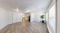 This thoughtfully designed unit at Law Modera in Federal Way, Washington, offers a practical and comfortable single-floor layout with three bedrooms, one bathroom, and a combined kitchen and living area. The open living room is bright and welcoming, featuring durable wood-style flooring, neutral white walls, and a textured ceiling. A hallway with a double-door closet provides convenient storage directly off the living space.

The kitchen is well-appointed with white shaker-style cabinetry, generous counter space, a stainless steel refrigerator, a black range, and a single-basin sink — all flowing seamlessly onto the same wood-style flooring found throughout the main living areas.

The primary bedroom is a comfortable size and includes a sliding double-door closet. The additional bedrooms feature plush carpeting, natural light from windows with outdoor greenery views, and baseboard heating. One bedroom also features direct access to the main entry door.

The bathroom is clean and functional, complete with a full tub-shower combination, a white vanity, and wood-style flooring. A hallway connects all rooms efficiently, contributing to the unit's practical flow. Overall, the space presents a clean, move-in-ready aesthetic with consistent finishes throughout.