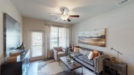 This single-story, two-bedroom, two-bathroom residence delivers a well-balanced layout with modern finishes throughout. The living area serves as the heart of the home, featuring wood-style flooring, a ceiling fan, and multiple windows alongside a glass-panel door that invite generous natural light. The kitchen is a standout, equipped with dark espresso cabinetry, light quartz countertops, stainless steel appliances including a range, microwave, and dishwasher, and a double-basin sink — all complemented by a breakfast bar for additional prep and dining space. Both bedrooms are carpeted and include ceiling fans, large windows, and closets. The primary bedroom features an en-suite bathroom with a wide vanity, dual sinks, white quartz countertops, and dark cabinetry. The second bathroom offers a full tub-shower combination with elegantly tiled surround walls and wood-style flooring. Additional conveniences include an in-unit washer and dryer. The overall aesthetic blends warm, neutral tones with contemporary dark accents, creating a cohesive and inviting atmosphere throughout the residence.