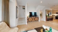 Located at 101 Chamomile Glen in Escondido, CA, this thoughtfully designed three-story home offers three bedrooms, four bathrooms, and a well-organized layout spread across three distinct levels. The entry-level houses an attached garage with direct interior access, providing convenient and secure parking. The main living floor features an open-plan living and dining room filled with natural light from multiple windows, complemented by light hardwood-style flooring. The kitchen is outfitted with stainless steel appliances, gray cabinetry, quartz countertops, a tile backsplash, and ample storage — a functional and stylish space for everyday cooking. A sleek powder bathroom on this level features textured wall coverings and a modern vessel sink. The upper floor hosts the bedrooms, including a well-proportioned primary suite, each accented with bold teal feature walls and plush carpeting. The bathrooms include tub-shower combinations with clean white tile surrounds and modern vanities. A dedicated laundry area with built-in cabinetry and wire shelving adds everyday convenience. Art-lined staircases with warm wood treads connect the floors, adding a gallery-like quality throughout. The home balances modern finishes with a warm, livable character.