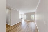 This well-appointed one-bedroom, one-bathroom residence at 117 Ridge Ln, Unit 104 in Waltham, MA offers a thoughtfully designed single-floor layout with a comfortable, functional living environment. The open living and dining area is finished with warm hardwood-style flooring, crown molding, and neutral-toned walls, creating a bright and welcoming atmosphere. Multiple windows allow natural light to flow throughout, with pleasant outdoor views adding to the airy feel of the space. The kitchen is efficiently laid out with light maple cabinetry, dark granite countertops, a breakfast bar peninsula, and a full suite of stainless steel appliances, including a refrigerator, electric range, and microwave. Adjacent to the kitchen is a dedicated in-unit laundry area equipped with a full-size washer and dryer. The bedroom is a comfortable, well-proportioned retreat featuring hardwood-style flooring, a ceiling fan, and natural light from dual windows. The bathroom includes a soaking tub and shower combination with white tile surround and grab bar fixtures. Storage is a standout feature, with five closets throughout — including a spacious walk-in closet with wire shelving — plus a utility room. Crown molding and clean white baseboards lend a polished finish throughout the home.