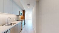 Located on Santa Monica Boulevard in the heart of West Los Angeles, this thoughtfully designed 1-bedroom, 2-bathroom residence offers a clean, modern aesthetic throughout. Light hardwood flooring flows seamlessly across every room, complementing the crisp white walls and creating a bright, cohesive atmosphere.

The galley-style kitchen is outfitted with flat-front cabinetry in soft grey and warm wood tones, stainless steel appliances including a built-in microwave and range, and a sleek countertop — all framing a corridor that opens naturally into the living area. The living room is a standout space, featuring a dramatic black spiral staircase, recessed lighting, and an open layout that maximizes the sense of space.

The bedroom is generously proportioned with large windows that invite abundant natural light and offer views of the surrounding cityscape. A dedicated walk-in closet provides multi-tier shelving and hanging storage on three walls. Both bathrooms are finished in a consistent modern style, each featuring stone-tiled walk-in showers with frameless glass enclosures, wood-toned vanities with undermount sinks, and wide-format mirrors with linear lighting. The overall ambiance is clean, contemporary, and well-appointed throughout.
