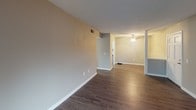 Located at 105 Cavalier Dr in Greenville, SC, this single-floor unit offers a practical and comfortable layout with a clean, neutral aesthetic throughout. The main living area greets you with rich, dark hardwood-style flooring, neutral gray walls, and a textured ceiling, creating a bright and open atmosphere. A ceiling fan provides added comfort, and the space flows naturally between the living and dining areas, offering a versatile floor plan.

The galley-style kitchen is thoughtfully designed with white cabinetry, granite-look countertops, a stainless steel sink, and matching stainless steel appliances, including a full-size refrigerator. Light wood-style flooring complements the cabinetry, and a window allows natural light to filter in.

The bedroom features wall-to-wall carpeting in a warm neutral tone, providing a cozy retreat with ample wall space for furniture placement.

The full bathroom is finished with dark hardwood-style flooring, a white vanity with a single sink, a large mirror with overhead lighting, and a tub-shower combination with tile surround and a curtain rod.

Throughout the unit, white baseboards provide a crisp contrast to the gray walls, and the overall design reflects a move-in-ready space with modern, functional finishes suited for everyday living in Greenville.