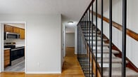 Located at 1942 MacKenzie Dr in Upper Arlington, Ohio, this multi-level home offers two bedrooms and two bathrooms spread across three thoughtfully laid-out floors. The main level welcomes you with a bright living room featuring warm hardwood flooring and a large sliding glass door that fills the space with natural light. The kitchen is well-appointed with oak cabinetry, white tile backsplash, light countertops, and a full suite of stainless steel appliances including a range, microwave, dishwasher, and refrigerator, complemented by durable wood-look vinyl flooring. One bathroom on the upper level features white subway tile surrounding a full soaking tub and shower, with a wood vanity and modern chrome fixtures. A second bathroom includes white tile wainscoting and a built-in countertop shelf. The spacious primary bedroom is carpeted and fitted with a ceiling fan, a wide window overlooking mature greenery, and ample closet space including both sliding and hinged doors. The second bedroom is similarly carpeted with neutral tones and dual doorways for convenient access. The basement level provides versatile additional space with grey vinyl plank flooring, recessed skylights, and a utility area housing the water heater and HVAC systems. A hallway and multiple staircases connect the levels seamlessly throughout.