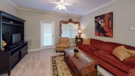 Located at 217 Carolina Forest Blvd in Jacksonville, NC, this single-floor residence offers a thoughtfully designed layout with comfortable living spaces throughout. Crown molding details add a refined touch to the interior.

The living room is warm and inviting, featuring plush carpet, a ceiling fan, and natural light streaming through blinds framed by decorative valances. A private exterior door provides convenient access directly from this space.

The galley-style kitchen is well-equipped with dark espresso cabinetry, granite-look countertops, black appliances including a refrigerator, range, and built-in microwave, along with durable tile-look flooring that adds a practical elegance.

Two bedrooms offer comfortable retreats, each with ceiling fans, carpeted floors, and windows that allow natural light. One bedroom features a walk-in closet, providing generous storage. Both rooms are spacious enough to accommodate full bedroom furniture sets.

Two full bathrooms mirror each other in design, each featuring granite-look countertops, white cabinetry vanities, tub-shower combinations, and wood-look flooring for easy maintenance.

A dedicated in-unit laundry area houses a full-size washer and dryer, adding everyday convenience. The overall ambiance is warm and residential, with neutral tones throughout creating a cohesive, welcoming atmosphere.