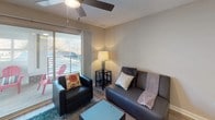 This single-storey space in Sidney offers a practical and well-appointed layout designed for comfortable everyday living. The open-concept kitchen and living area forms the heart of the unit, with wood-look flooring flowing throughout. The kitchen is equipped with stainless steel appliances, including a refrigerator and electric range, complemented by white cabinetry and light stone-look countertops. A peninsula with seating for two provides a casual dining option and separates the kitchen from the living space.

The living area is bright and welcoming, featuring a ceiling fan, a sliding glass door that opens onto a private balcony with outdoor seating, and views of surrounding trees. Natural light fills the space through the large glass door.

The bedroom is finished with plush carpeting and features a window with horizontal blinds, allowing for adjustable natural light. The neutral wall tones throughout the space create a calm, cohesive atmosphere.

The bathroom includes a tub-shower combination with a curved curtain rod, a stone-patterned tile floor, and a vanity topped with a light marble-style countertop, providing functional and clean finishes throughout.