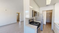 This well-appointed single-floor residence offers a clean, modern aesthetic throughout, with thoughtful updates that balance comfort and functionality. The open-concept living area is bathed in natural light from large windows that frame views of palm trees and surrounding greenery, creating an airy and welcoming atmosphere. Light wood-style flooring runs through the main living spaces, complementing the bright white walls and neutral finishes.

The galley-style kitchen is efficiently designed and beautifully updated, featuring crisp white cabinetry that extends to the ceiling for generous storage, a classic white subway tile backsplash, and stone-look countertops. Stainless steel appliances include a gas range, built-in microwave, dishwasher, and refrigerator, making this a fully equipped cooking space.

The bedrooms are carpeted for comfort and each offers windows with pleasant outdoor views, including hillside and palm tree scenery. Sliding mirrored closet doors provide practical storage solutions. The bathroom is clean and functional, featuring a full soaking tub with shower and a bright window that allows natural light to fill the space.

Overall, the residence presents a fresh, move-in-ready environment with a cohesive neutral palette, modern fixtures, and an abundance of natural light throughout.