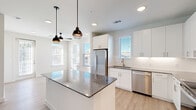 Located at 4600 East McKinney Street in Denton, TX, this well-appointed 2-bedroom, 2-bathroom residence offers a thoughtfully designed single-floor layout. The open-concept kitchen serves as the heart of the home, showcasing crisp white cabinetry, a striking granite-topped island illuminated by stylish industrial pendant lights, and a full suite of stainless steel appliances including a refrigerator, range, microwave, and dishwasher. Light wood-look flooring and a white subway tile backsplash complete the clean, contemporary aesthetic, while multiple windows flood the space with natural light.

Both bedrooms are carpeted and feature ceiling fans, generous natural light from large windows, and access to dedicated closets with built-in shelving and hanging rods. The primary bedroom is a comfortable size and connects to its own bathroom, which includes a wide granite-topped vanity, white cabinetry, a large framed mirror, and wood-look flooring. The second bathroom mirrors the same refined finishes and is conveniently accessible from the hallway. A connecting hallway links all rooms efficiently, contributing to a cohesive and functional floor plan throughout the residence.