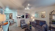 This single-story, two-bedroom, one-and-a-half-bath residence offers a practical and comfortable layout designed to maximize its well-proportioned footprint. The living area serves as the heart of the home, featuring plush carpet, neutral walls, and a ceiling fan with integrated lighting. The space comfortably accommodates a seating arrangement and opens toward the kitchen via a convenient pass-through counter, enhancing connectivity between the two areas.

The kitchen is efficiently designed with a galley-style configuration, featuring white cabinetry, light countertops, black appliances including a range and refrigerator, and warm hardwood-style flooring that contrasts the cabinetry for a clean, cohesive look.

Both bedrooms are carpeted and include ceiling fans, natural light from windows with blinds, and closet storage. The primary bedroom offers generous space for a full furniture arrangement, while the second bedroom also includes a reach-in closet.

The bathrooms feature white cabinetry, light countertops, large mirrors, and bright vanity lighting. The overall ambiance throughout the unit is calm and neutral, providing a comfortable and move-in-ready living environment.