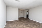 This single-story home offers a practical and comfortable layout with a variety of thoughtful finishes throughout. The main living area is anchored by rich, dark hardwood-style flooring that flows seamlessly into the dining space, creating an open and cohesive feel. A glass-paneled door leads to a bright enclosed porch, lined with wide windows and blinds that bathe the area in natural light while offering views of the surrounding outdoor space.

The kitchen is well-equipped with dark espresso cabinetry, granite-style countertops, a tile backsplash, and a louvered pantry door that adds a classic touch. Ample counter space on both sides makes the kitchen both functional and stylish.

The bedrooms feature neutral-toned carpet and large windows fitted with blinds, allowing for adjustable natural light. The textured ceilings carry throughout the home, adding visual character to each room.

The bathroom is finished with dark wood cabinetry, a granite-topped vanity, wood-look flooring, and a full tub and shower combination set against a neutral, textured wall. The overall palette of warm taupes, grays, and deep wood tones gives this home a cohesive, move-in-ready aesthetic that balances comfort and practicality.