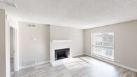 This thoughtfully designed 1-bedroom, 1-bathroom unit spans a single floor, offering an efficient and comfortable layout across five distinct spaces. The living room serves as the centerpiece of the home, showcasing a classic tile-surround fireplace with a clean white mantel that anchors the room. Light-toned luxury vinyl plank flooring runs throughout the main living areas, reflecting natural light that streams in through large windows fitted with horizontal blinds. Neutral warm-gray walls and a textured ceiling complete the bright, airy aesthetic.

The kitchen is well-equipped with white shaker-style cabinetry featuring gold hardware, light quartz countertops, a stainless steel sink, and a white subway tile backsplash. Stainless steel appliances, including a refrigerator, range, and dishwasher, add a modern touch.

The bedroom offers a comfortable, carpeted retreat with a dedicated window for natural light and direct access to the bathroom. The bathroom features a white vanity with quartz countertops, an undermount sink, and a well-lit mirror, with a hallway connecting it seamlessly to the rest of the unit.

Overall, the space presents a clean, neutral palette that is move-in ready and versatile for a variety of interior styles.