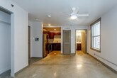 Located at 1114 Baltimore Ave in the heart of Kansas City, MO, this single-floor urban unit offers a thoughtfully designed open layout with an industrial-modern aesthetic. Polished concrete floors run throughout the entire space, lending a sleek, contemporary character that ties each area together seamlessly.

The main living area is bright and open, featuring exposed ceiling beams, a ceiling fan, and windows with dark wood trim that frame views of the surrounding brick urban streetscape, allowing natural light to filter in. A spacious closet with sliding doors provides ample built-in storage.

The kitchen is efficiently laid out and well-appointed, featuring rich dark wood cabinetry, a classic white subway tile backsplash, light stone countertops, stainless steel appliances including a refrigerator, range, and microwave, and recessed lighting overhead. The kitchen flows naturally into the living space, making the layout feel cohesive and functional.

The bathroom is clean and modern, finished with large-format neutral stone-toned wall tiles surrounding a full soaking tub and shower combination, complemented by chrome fixtures. The unit also includes a utility panel conveniently located near the kitchen entry. Overall, the space balances urban industrial design with practical, comfortable living in a prime Kansas City location.