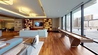 This elegantly designed single-floor amenity space offers a seamless blend of upscale comfort and modern urban living. Rich hardwood flooring flows throughout, unifying the multiple functional zones within the open-concept layout.

The expansive lounge area is anchored by generous sectional seating, layered lighting including recessed fixtures and cove illumination, and a built-in wood shelving unit with integrated display lighting and a mounted flat-screen television. A shuffleboard table adds a refined recreational element alongside floor-to-ceiling windows that frame striking cityscape views.

Adjacent to the lounge, a formal dining area accommodates a large dark-wood dining table beneath a sculptural cluster of globe pendant lights suspended on brass rods. Floor-to-ceiling glazing connects this space visually to the outdoor terrace beyond.

The gourmet kitchen is outfitted with flat-front light-grey cabinetry, a dramatic veined stone backsplash, a waterfall-edge island with bar seating, stainless steel appliances including a built-in oven, and a warm wood-paneled ceiling with pendant lighting. A casual dining nook with a round table sits alongside a large window.

The outdoor terrace, accessible via a full wall of sliding glass doors with dark frames, provides a generous open-air entertaining area with seating and panoramic views of the surrounding urban skyline.