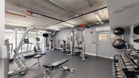 Located at 35 Southwest 6th Avenue in Miami's vibrant Brickell neighborhood, this fitness center offers a well-appointed exercise space designed to support a comprehensive workout routine. The single-level gym features an industrial-style aesthetic, with an exposed concrete ceiling, visible HVAC ductwork, and linear fluorescent lighting that gives the space a clean, functional character. Dark rubber flooring throughout provides both durability and comfort underfoot.

The cardio zone is anchored by a row of Star Trac treadmills and an elliptical trainer positioned alongside floor-to-ceiling glass windows, flooding the area with natural light and offering open views of the surrounding streetscape. A wall-mounted television provides entertainment during workouts.

The strength training section is well-equipped with a Hoist multi-station cable machine, a variety of selectorized weight machines, and adjustable benches suited for a range of exercises. A dedicated free weights area features a full rack of dumbbells and a large wall mirror, allowing users to monitor their form. The space is efficiently organized to maximize the available floor area while maintaining clear pathways between equipment stations. Overall, the gym delivers a practical and fully functional fitness environment in the heart of Miami.