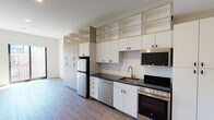 Located at 122 Oakes St SW in the heart of Grand Rapids, Michigan, this modern single-floor studio offers a thoughtfully designed open layout that seamlessly connects the kitchen and living areas. The kitchen is a standout feature, equipped with a full suite of stainless steel appliances — including a refrigerator, dishwasher, electric range, and over-the-range microwave — complemented by dark granite countertops, a stainless undermount sink, and a classic white subway tile backsplash. Abundant white cabinetry, including open upper shelving, provides generous storage throughout. Durable wood-look flooring runs throughout the unit, lending warmth and continuity to the space. The open living area is bright and functional, with recessed lighting overhead and a large window and sliding door leading to a private balcony, inviting natural light and outdoor views. The bathroom is clean and well-appointed, featuring a granite-topped vanity with an illuminated mirror, and accessibility-friendly fixtures including grab bars. A solid entry door with a keypad lock completes this well-designed, move-in-ready urban residence.