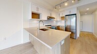 Located on the 10th floor at 825 Fort Street in the heart of downtown Victoria, BC, this modern two-bedroom, two-bathroom unit offers a well-designed layout with clean, contemporary finishes throughout. Light-toned laminate wood flooring runs seamlessly across the entire space, complemented by crisp white walls and recessed lighting that create a bright, airy atmosphere.

The kitchen is a functional centrepiece, featuring a large peninsula with an undermount sink and stone countertops, warm wood-toned lower cabinetry paired with white upper cabinets, a classic white tile backsplash, and a full suite of stainless steel appliances including a range, dishwasher, and refrigerator. Track lighting overhead adds both style and practicality.

Both bedrooms are comfortably sized with tall, narrow windows that frame elevated city views of Victoria's downtown core, flooding the rooms with natural light. Exposed concrete ceiling details in select areas lend an urban, industrial character to the space.

The two bathrooms are finished with warm wood-grain vanity cabinetry and stone countertops. One features a glass-enclosed walk-in shower, while the other offers a full soaker tub. Frosted glass interior doors and a dedicated closet complete the thoughtfully arranged floor plan.