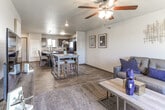 This two-story residence offers a thoughtfully arranged layout spread across two levels, connected by a staircase visible in the floor plan. The main level centers around an open living area finished with durable wood-look flooring and carpet, where a ceiling fan with integrated lighting provides both comfort and illumination. The living room offers ample space for seating and entertainment, with natural light filtering in through a window dressed with teal patterned curtains.

The kitchen is a functional highlight, featuring dark espresso cabinetry, light countertops, and black appliances including a range, microwave, and refrigerator. A peninsula island with seating provides a casual dining option, while pendant lighting overhead adds a polished touch. Wood-look flooring ties the kitchen and entryway together seamlessly.

The bathrooms are finished with tile flooring and dark vanity cabinetry topped with light counters, offering a clean, modern aesthetic. Each includes a tub-shower combination.

The bedrooms are located on the upper level and feature vaulted ceilings, plush carpet, and windows offering outdoor views of the surrounding neighborhood. The angled ceilings add architectural character, contributing to an airy, comfortable atmosphere throughout the private quarters.