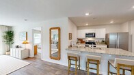 Located at 4118 Hobblebush Dr in Leland, NC, this well-appointed single-story home offers four bedrooms, two bathrooms, and a thoughtfully designed layout. The open-concept living, dining, and kitchen area forms the heart of the home, anchored by a bright living room with wood-look flooring, a ceiling fan, and natural light streaming through large windows and a sliding glass door. The kitchen is a standout feature, showcasing crisp white cabinetry, granite countertops, stainless steel appliances including a range, microwave, and refrigerator, and a peninsula with bar seating for three — ideal for casual dining or entertaining. A dedicated pantry adds convenient storage. The primary bedroom is a comfortable retreat with soft carpeting, a natural light-filled window, and access to an en-suite bathroom featuring granite vanity counters, white cabinetry, wood-look tile flooring, and a glass-enclosed walk-in shower. Three additional bedrooms each offer carpeted floors and individual closets, with seven closets total throughout the home. A dedicated laundry room houses a full-size washer and dryer with overhead wire shelving. The attached garage provides a spacious, clean concrete-floored space with an automatic opener. This home combines practical functionality with clean, modern finishes throughout.