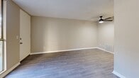 Located at 1101 Dumont Blvd in Las Vegas, NV, this efficiently designed single-floor unit offers a practical and well-appointed layout. The living room serves as the central gathering space, featuring light gray wood-look plank flooring, neutral beige walls, crisp white baseboards, and a textured ceiling. A ceiling fan with a built-in light fixture provides both comfort and illumination. A large window adjacent to the front door allows natural light to fill the space and offers views of the surrounding outdoor area.

The kitchen is positioned adjacent to the living area and is equipped with a refrigerator and stovetop, making efficient use of the available space. A dedicated closet provides additional storage.

The unit includes two bathrooms, each continuing the wood-look flooring and textured ceiling found throughout. One bathroom features white cabinetry with dark hardware, a white vanity sink, and tile-accented walls, with direct access to the adjoining spaces for added convenience.

Throughout the unit, the consistent use of neutral tones, clean finishes, and functional design elements creates a cohesive and low-maintenance living environment. The combination of natural light, modern flooring, and ceiling fans contributes to a comfortable and practical atmosphere suited to everyday living in Las Vegas.