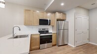 This well-appointed one-bedroom, one-bathroom unit in Webster, NY offers a thoughtfully designed single-floor layout that maximizes every square foot. The open-concept kitchen and living/dining area serves as the heart of the home, featuring light wood-style flooring, recessed lighting, and a window that brings in natural light. The kitchen is equipped with stainless steel appliances—including a refrigerator, range, microwave, and dishwasher—complemented by light maple shaker-style cabinetry, a white quartz countertop, a subway tile backsplash, and a stainless steel sink. The layout flows naturally into the combined dining and living area, creating a cohesive and functional space. The bedroom offers plush carpeting, neutral-toned walls, and a window with a view of surrounding greenery, providing a calm and private retreat. The bathroom stands out with elegant marble-patterned tile covering both the floors and the walls of the glass-enclosed walk-in shower, paired with a dark-toned vanity and white countertop. Additional features include a dedicated laundry area, a hallway, and a closet for ample storage. The unit presents a clean, contemporary aesthetic throughout.