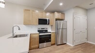 This well-appointed one-bedroom, one-bathroom unit in Webster, NY offers a thoughtfully designed single-floor layout that maximizes every square foot. The open-concept kitchen and living/dining area serves as the heart of the home, featuring light wood-style flooring, recessed lighting, and a window that brings in natural light. The kitchen is equipped with stainless steel appliances—including a refrigerator, range, microwave, and dishwasher—complemented by light maple shaker-style cabinetry, a white quartz countertop, a subway tile backsplash, and a stainless steel sink. The layout flows naturally into the combined dining and living area, creating a cohesive and functional space. The bedroom offers plush carpeting, neutral-toned walls, and a window with a view of surrounding greenery, providing a calm and private retreat. The bathroom stands out with elegant marble-patterned tile covering both the floors and the walls of the glass-enclosed walk-in shower, paired with a dark-toned vanity and white countertop. Additional features include a dedicated laundry area, a hallway, and a closet for ample storage. The unit presents a clean, contemporary aesthetic throughout.