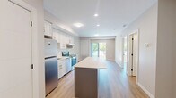 Located at 1100 Afton Drive in Windsor, Ontario, this one-bedroom, one-bathroom unit offers a thoughtfully designed layout that maximizes every square foot. The open-concept living and kitchen area forms the heart of the space, featuring crisp white shaker cabinetry, a subway tile backsplash, stainless steel appliances including a refrigerator, electric range, and dishwasher, and a central kitchen island with a clean quartz-style countertop — ideal for meal prep or casual dining. Light wood-tone flooring runs throughout, complementing the neutral, warm-toned walls and creating a cohesive, modern aesthetic. Recessed lighting keeps the main living area bright, while a sliding glass door opens to a balcony, inviting natural light and outdoor views into the space. In-suite laundry is also included, adding everyday convenience. The bedroom is a comfortable, well-proportioned retreat with a large sliding-door closet and continued warm flooring. The bathroom is cleanly finished with a white vanity, wood-tone flooring, and a full walk-in shower. Throughout the unit, matte black hardware accents provide a contemporary touch against the predominantly white palette, resulting in a fresh, move-in-ready residence.