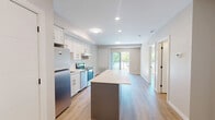 Located at 1100 Afton Drive in Windsor, Ontario, this one-bedroom, one-bathroom unit offers a thoughtfully designed layout that maximizes every square foot. The open-concept living and kitchen area forms the heart of the space, featuring crisp white shaker cabinetry, a subway tile backsplash, stainless steel appliances including a refrigerator, electric range, and dishwasher, and a central kitchen island with a clean quartz-style countertop — ideal for meal prep or casual dining. Light wood-tone flooring runs throughout, complementing the neutral, warm-toned walls and creating a cohesive, modern aesthetic. Recessed lighting keeps the main living area bright, while a sliding glass door opens to a balcony, inviting natural light and outdoor views into the space. In-suite laundry is also included, adding everyday convenience. The bedroom is a comfortable, well-proportioned retreat with a large sliding-door closet and continued warm flooring. The bathroom is cleanly finished with a white vanity, wood-tone flooring, and a full walk-in shower. Throughout the unit, matte black hardware accents provide a contemporary touch against the predominantly white palette, resulting in a fresh, move-in-ready residence.