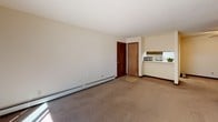 Located at 1208 Sweeney Dr in Middleton, Wisconsin, this single-floor unit offers a straightforward, functional layout designed for comfortable everyday living. The living area is generously proportioned, featuring neutral carpet flooring, white vertical panel accent walls, and a baseboard heating system. A sliding glass door floods the space with natural light and provides direct access to an outdoor area, offering pleasant views of surrounding greenery. A wall-mounted air conditioning unit ensures year-round comfort.

The kitchen is efficiently arranged in a galley-style configuration, featuring warm wood-toned cabinetry that extends to both upper and lower sections, providing ample storage. A white electric coil range with an overhead exhaust hood, a stainless steel sink, and a full-size refrigerator complete the kitchen's functional offerings. A drop-panel ceiling with diffused lighting illuminates the workspace, and a pass-through counter connects the kitchen to the main living space.

The bedroom is a calm, carpeted retreat with a wide closet offering built-in shelving and hanging rods for generous storage. The bathroom includes an extended vanity countertop with an integrated sink and a large mirror, accompanied by a drop-panel ceiling and tile-style flooring. Throughout the unit, neutral tones and practical finishes create a clean, livable atmosphere.