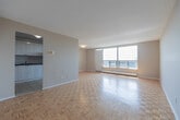 Located at 365 Kennedy Rd in Brampton, Ontario, this two-bedroom unit offers a well-organized single-level layout with a bright and practical design throughout. The living room is the standout space, featuring warm parquet wood flooring, large floor-to-ceiling windows, and direct access to a private balcony that frames elevated views of the surrounding Brampton cityscape. Abundant natural light fills the room, creating an airy and open atmosphere.

The kitchen is thoughtfully laid out with white cabinetry, dark granite-style countertops, tile flooring, and stainless steel appliances including a refrigerator and range. An open passageway connects the kitchen directly to the living area, enhancing the flow of the space.

Both bedrooms continue the parquet flooring theme and are finished in neutral tones. The primary bedroom is generously proportioned and features a window with city views and baseboard heating. The second bedroom is compact and bright, also with a window overlooking the city. The primary bedroom benefits from dual closets, providing ample storage.

Throughout the unit, neutral warm-grey walls and clean white trim provide a cohesive and understated aesthetic, making the space feel move-in ready and versatile.