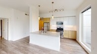 This contemporary single-floor residence is defined by clean lines, an abundance of natural light, and a thoughtfully designed open layout. Large floor-to-ceiling windows throughout the living areas frame sweeping urban views of the surrounding cityscape and tree-lined streets, flooding the interior with daylight and creating a seamless connection between indoors and out.

The open-concept kitchen is a standout feature, showcasing a large waterfall-edge island with an integrated sink, a combination of white upper cabinetry and warm wood-toned lower cabinets, subway tile backsplash, and a full suite of stainless steel appliances including a gas range, microwave, and refrigerator. Pendant lighting adds a refined finishing touch overhead.

Light-toned hardwood-style flooring flows consistently throughout the space, lending warmth and visual continuity. The living and sleeping areas are generously proportioned, each benefiting from natural light and views of the urban environment outside. A dedicated walk-in closet with dual hanging rods and shelving provides ample storage.

The bathrooms are finished with crisp white subway tile surrounds in the tub/shower combinations and chrome fixtures, maintaining the home's clean, modern aesthetic. A long, well-lit hallway with recessed lighting connects the rooms, completing this polished and functional urban residence.
