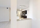 Located at 20941 San Simeon Way in Miami, Florida, this single-floor residence offers a thoughtfully designed layout with a clean, contemporary aesthetic throughout. Light-toned tile flooring flows seamlessly across the living areas, bedrooms, and wet spaces, creating a cohesive and easy-to-maintain interior.

The kitchen is a standout feature, appointed with rich dark espresso cabinetry — some with glass-front upper doors — and granite countertops. A full suite of stainless steel appliances includes a refrigerator, electric range, and built-in microwave. A peninsula with a granite overhang provides a casual dining or prep surface and opens directly to the living area, supporting an open-concept flow. Track and overhead lighting illuminate the kitchen effectively.

The living space is generously proportioned, bright, and open, with a ceiling fan and access to natural light through slatted windows. Bedrooms are well-sized with the same tile flooring and natural light from windows. The primary suite includes a walk-in closet outfitted with wire shelving systems for organized storage.

Bathrooms feature dark vanity cabinetry with granite countertops and undermount sinks, consistent with the kitchen's design language. One bathroom includes a shower/tub combination. A dedicated laundry room houses side-by-side Whirlpool washer and dryer units with overhead wire shelving for additional storage.