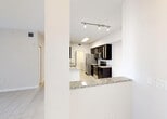 Located at 20941 San Simeon Way in Miami, Florida, this single-floor residence offers a thoughtfully designed layout with a clean, contemporary aesthetic throughout. Light-toned tile flooring flows seamlessly across the living areas, bedrooms, and wet spaces, creating a cohesive and easy-to-maintain interior.

The kitchen is a standout feature, appointed with rich dark espresso cabinetry — some with glass-front upper doors — and granite countertops. A full suite of stainless steel appliances includes a refrigerator, electric range, and built-in microwave. A peninsula with a granite overhang provides a casual dining or prep surface and opens directly to the living area, supporting an open-concept flow. Track and overhead lighting illuminate the kitchen effectively.

The living space is generously proportioned, bright, and open, with a ceiling fan and access to natural light through slatted windows. Bedrooms are well-sized with the same tile flooring and natural light from windows. The primary suite includes a walk-in closet outfitted with wire shelving systems for organized storage.

Bathrooms feature dark vanity cabinetry with granite countertops and undermount sinks, consistent with the kitchen's design language. One bathroom includes a shower/tub combination. A dedicated laundry room houses side-by-side Whirlpool washer and dryer units with overhead wire shelving for additional storage.