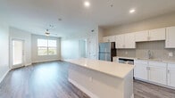 This 2-bedroom, 2-bathroom single-floor residence offers a thoughtfully designed open-concept layout that maximizes functionality and comfort. The combined kitchen and living area serves as the heart of the home, featuring a large central island with a crisp white quartz countertop, white shaker-style cabinetry, a classic subway tile backsplash, and a full suite of stainless steel appliances including a refrigerator, range, microwave, and dishwasher. Wood-style plank flooring flows seamlessly throughout the main living areas, complemented by neutral wall tones and recessed lighting. The living room benefits from a ceiling fan and large windows that invite abundant natural light and outdoor views of the surrounding greenery. Both bedrooms are generously sized, each equipped with a ceiling fan and windows offering natural light. The spacious primary bedroom connects to a well-organized walk-in closet with built-in shelving and hanging rods. Each bathroom features a white vanity with stone-topped counters and tile flooring. Two dedicated closets provide additional storage throughout the residence, contributing to an overall clean, modern, and move-in-ready aesthetic.