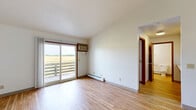 Located at 1810 Liberty Dr in Mount Pleasant, Michigan, this one-bedroom, one-bathroom unit offers a practical and comfortable single-floor layout. The combined living and dining area is bright and open, featuring light wood-style flooring, a textured ceiling, and a sliding glass door that leads to a private deck overlooking expansive open fields — filling the space with natural light and scenic views. Baseboard heating is found throughout, and a wall-mounted air conditioning unit serves the main living area.

The galley-style kitchen is efficiently designed with white cabinetry featuring wood trim accents, ample upper and lower storage, white appliances including an electric range and refrigerator, and a double sink — all complemented by the same light wood-style flooring.

The bedroom is a comfortable size, finished with plush carpeting and two closets, offering a quiet and cozy retreat. The full bathroom includes a vanity with storage, a toilet, and a tub/shower combination, finished with the same warm wood-style flooring found throughout the unit.

Additional highlights include a dedicated laundry area, a hallway connecting the main rooms, and a bold blue entry door that adds a welcoming touch to the space.