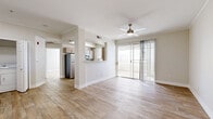 Located in Peoria, Arizona, this well-appointed 1-bedroom, 1-bathroom unit offers a thoughtfully designed single-level layout with a clean, modern aesthetic throughout. Warm wood-look flooring flows seamlessly across every room, complemented by crisp white trim and neutral-toned walls that create a bright and welcoming atmosphere. The open-concept living room is generously sized, featuring crown molding, a ceiling fan, and a sliding glass door that fills the space with natural light while providing direct access to an outdoor patio. An adjacent half-wall separates the galley-style kitchen, which is equipped with stainless steel appliances including a refrigerator and range, contemporary flat-front cabinetry in a warm wood finish, and light quartz countertops. A window above the sink brings in additional natural light. The bedroom offers comfortable proportions, its own sliding patio door with outdoor views, a ceiling fan, and direct access to a spacious walk-in closet with wire shelving. The bathroom features a full tub-shower combination, a modern vanity with wood-tone cabinetry, a white countertop, and a well-lit mirror. A dedicated laundry room houses a full-size washer and dryer with overhead cabinetry for additional storage, rounding out this functional and inviting home.