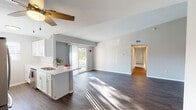 Located at 11443 Boulder Dr in Lowell, Michigan, this single-floor home offers a thoughtfully designed open-concept layout with a bright, airy ambiance throughout. The living area features vaulted ceilings, dark hardwood-style flooring, and a ceiling fan, with natural light streaming in through a sliding glass door that opens to an outdoor space. The kitchen is well-appointed with crisp white cabinetry, gleaming quartz countertops, stainless steel appliances including a French door refrigerator and range, and a peninsula that connects seamlessly to the living space. A secondary kitchen view reveals a galley-style workspace with ample upper and lower cabinetry and a natural light-filled window. The bedrooms are carpeted and comfortable, each featuring windows that invite natural light, with one room also equipped with a ceiling fan. The home includes two bathrooms — a full bath with a white vanity, large mirror, and shower-tub combination, and a second bath with a walk-in shower and hardwood-style flooring. Neutral gray walls and clean white trim create a cohesive, modern aesthetic throughout, making this a move-in ready home in a welcoming Michigan community.