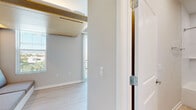 Located at 1114 W Carmen St in Tampa, FL, this efficiently designed single-floor studio makes smart use of every square foot through thoughtful modern design. The main living area features light wood-look flooring, neutral gray walls, and a built-in Murphy bed system with integrated lighting and a bench seat, maximizing the functionality of the space without sacrificing style.

The kitchen is well-appointed with light wood cabinetry, stainless steel appliances including a refrigerator, electric range, microwave, and dishwasher, along with a clean white countertop and a recessed ceiling with can lighting. Floor-to-ceiling vertical blinds frame a large sliding glass door that opens to a balcony, flooding the space with abundant natural light and offering views of the surrounding neighborhood.

The hallway connects the main living area to the full bathroom, which features light tile flooring, a single-sink vanity with light wood cabinetry and brushed gold hardware, and a full tub/shower combination with white subway tile surround. The overall design aesthetic is clean, contemporary, and minimalist, making this a highly functional space ideal for those seeking modern urban living in the heart of Tampa.
