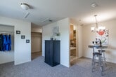 Located at 1501 Little Gloucester Rd in Blackwood, NJ, this single-floor unit offers a practical and well-organized layout across its four distinct spaces. The kitchen features warm honey-toned wood cabinetry with ample upper and lower storage, light countertops with a stainless steel sink, wood-look flooring, and white appliances including a gas range and refrigerator, creating a functional and efficient cooking environment. The dining area is a cozy, carpeted space illuminated by an elegant multi-arm chandelier, with large vertical blinds covering a wide window that allows for natural light control. The hallway connects the living spaces and provides access to generous built-in closet storage, including open shelving and a hanging rod, maximizing organization throughout the unit. The bathroom is clean and bright, finished with light wood-look flooring, a white vanity with under-sink storage, a toilet, and a full tub-shower combination accented by white tile and a classic striped curtain. Neutral tones and light-colored walls throughout the unit create a cohesive, airy ambiance, while carpeted living areas add a sense of warmth and comfort to this efficiently designed space.