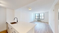 Located on the 29th floor at 100 Christopher Columbus Drive in Jersey City, this one-bedroom, one-bathroom residence offers a well-designed layout with modern finishes throughout. Light hardwood flooring runs continuously across the entire unit, lending warmth and cohesion to every room.

The combined kitchen and living area forms the heart of the home. The kitchen is outfitted with white shaker cabinetry, a white quartz countertop, stainless steel appliances including a French door refrigerator, and track lighting overhead. The adjacent living area is bright and open, with large floor-to-ceiling windows framing sweeping views of the Jersey City skyline and beyond.

The bedroom is a well-proportioned retreat, featuring its own oversized window with striking city views and ample wall space. Crisp white walls and the warm wood flooring create a clean, inviting atmosphere.

The bathroom is a standout feature, showcasing a classic black-and-white hexagonal tile floor, white subway tile walls, a white vanity with black hardware, a framed rectangular mirror, and a full soaking tub with shower. The coordinated matte black fixtures add a contemporary, refined touch.

A hallway connects the rooms efficiently, maintaining a logical and private flow throughout the unit. Clean white walls and abundant natural light from multiple exposures give the entire space a bright, airy character.