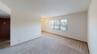 This single-floor residence in Georgetown South offers a straightforward, functional layout designed for comfortable everyday living. The entry corridor features tile flooring and warm wood-toned doors, providing a welcoming transition into the main living areas. A louvered closet door near the entry offers convenient storage access.

The living room is generously sized, finished with neutral carpet and bright white walls that reflect natural light from a wide multi-pane window overlooking mature trees. A ceiling fan adds both comfort and airflow. The open feel of the space is enhanced by its clean, unobstructed layout.

The galley-style kitchen is efficiently organized, with warm honey-toned cabinetry lining both sides, providing ample storage. It includes a coil-burner electric range, a full-size refrigerator, a stainless steel sink, and a ventilation hood. Tile flooring runs throughout the kitchen and connects seamlessly to the entryway.

The bedroom areas feature soft carpeting and windows with blinds that frame views of surrounding greenery, allowing natural light while maintaining privacy. A ceiling vent confirms central HVAC throughout the unit.

The bathroom is clean and functional, featuring a full-size soaking tub with an overhead shower, a white surround with built-in shelving, chrome fixtures, and a towel bar.